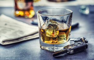 lowball glass with whiskey with a car fob next to it representing drinking and driving